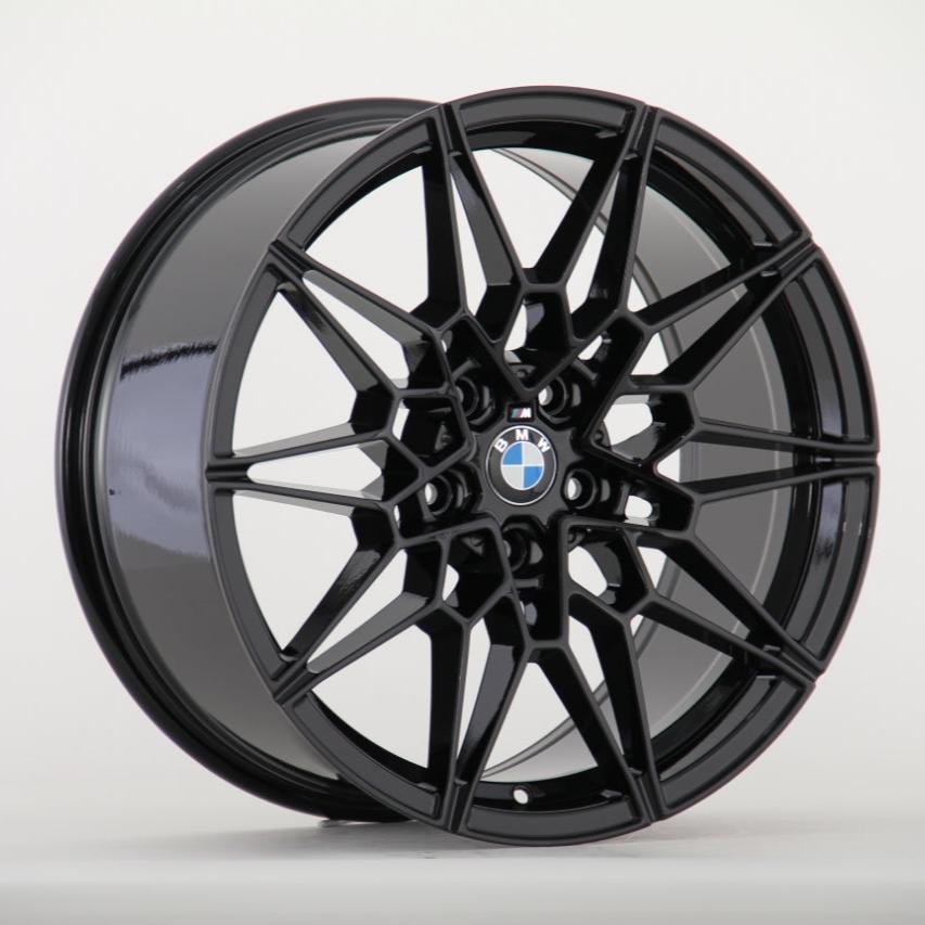 A black, multi-spoke car wheel rim features a central BMW logo, set against a plain white background.
