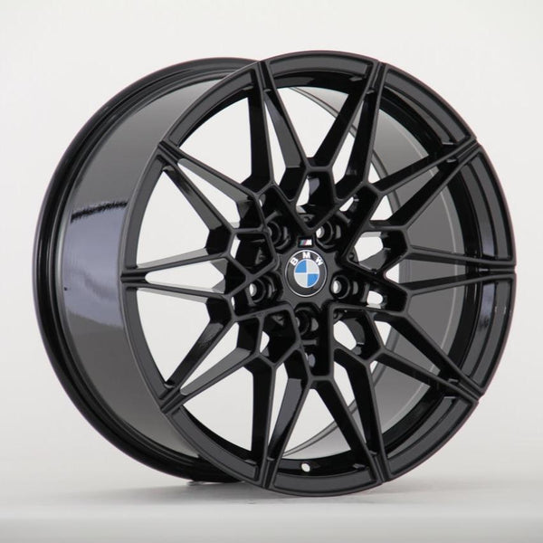 A black, multi-spoke car wheel rim features a central BMW logo, set against a plain white background.