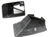 Carbon fiber intake ducts rest on a white surface, one upright and one on its side. A small silver logo reads 