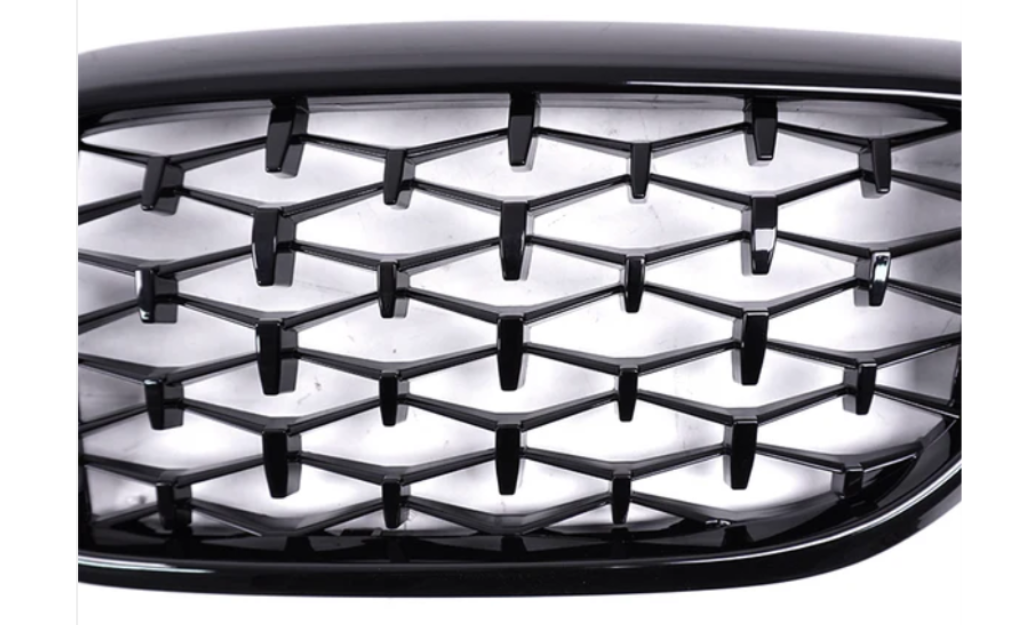 Honeycomb-patterned black grille in a car front view, with a glossy finish. The grille has a three-dimensional design, appearing against a bright, neutral background. No text is present.