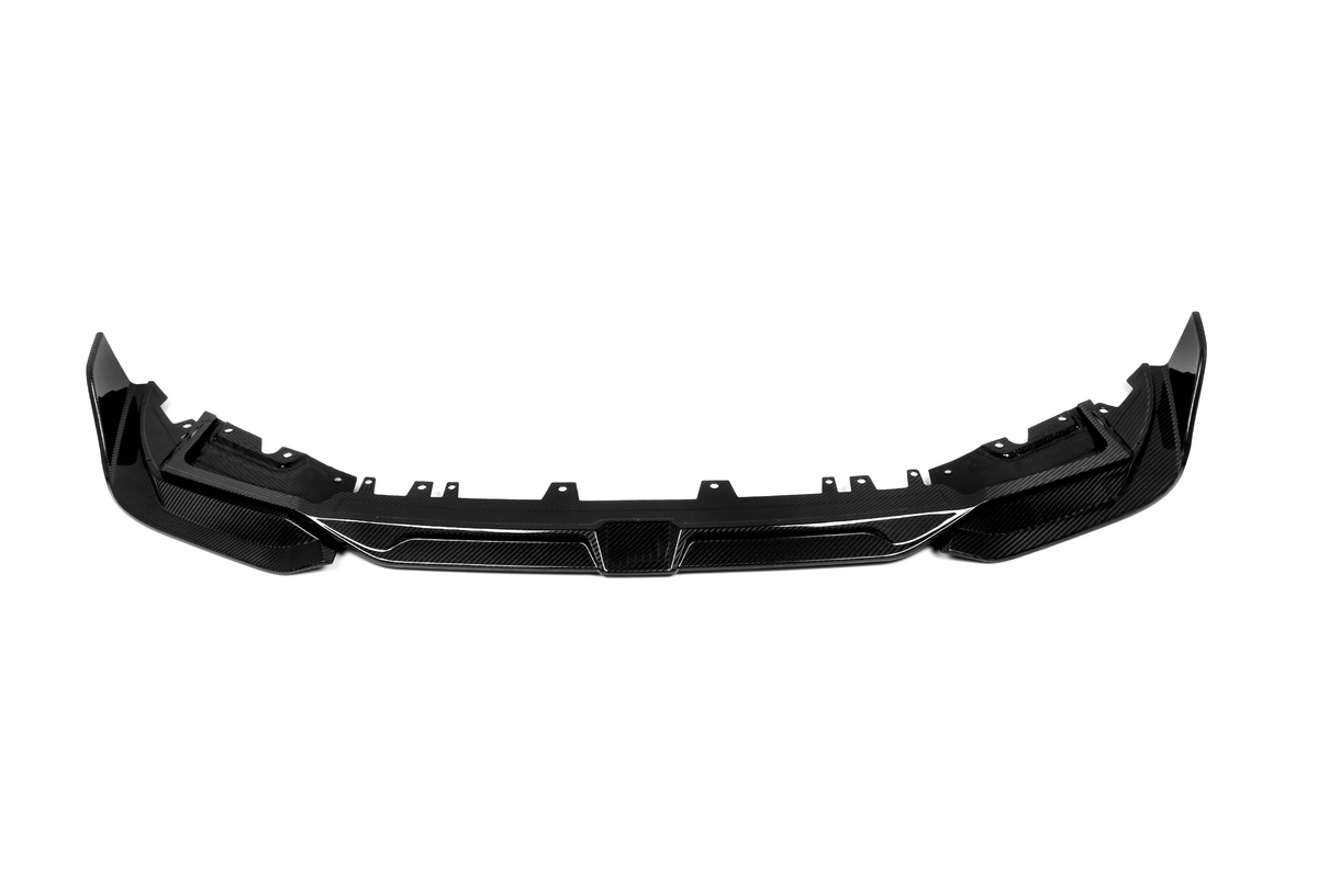 A sleek, black carbon fiber car front bumper is lying flat, designed for aerodynamic enhancement, within a plain white background for contrast.