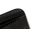 A close-up of a carbon fiber object with a visible textured pattern, featuring a rounded corner, set against a plain white background.