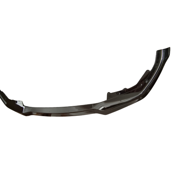 A glossy black car bumper lies horizontally in a featureless white background, showcasing a curved shape with mounting points and sleek edges.