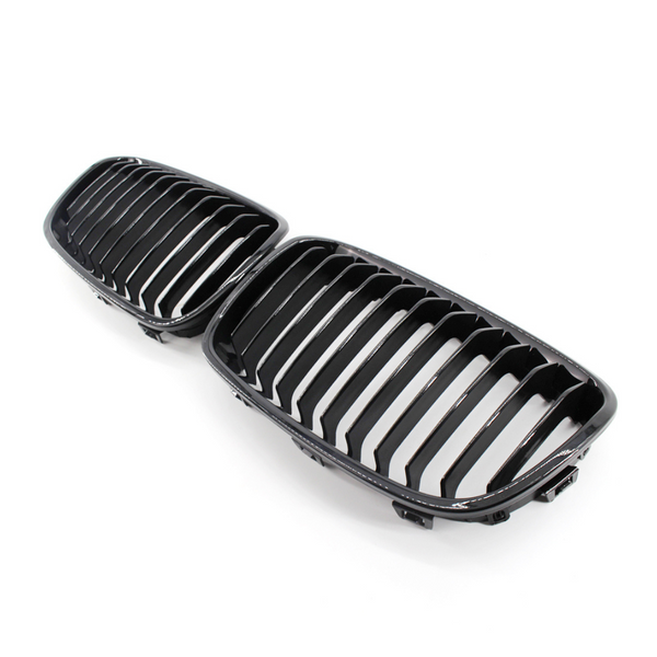 A pair of black, glossy car grilles featuring vertical slats, positioned side by side on a plain white background.