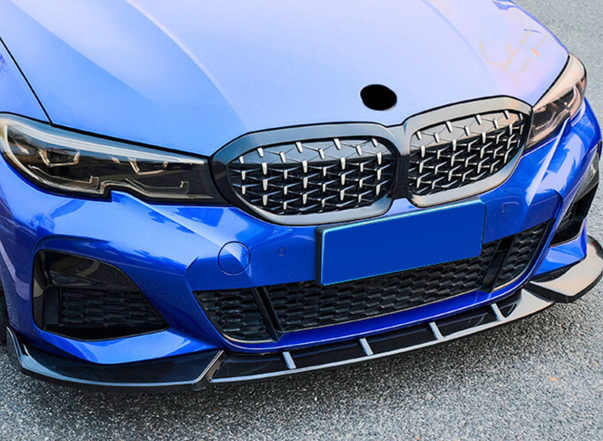 Blue car front with a distinctive grille and headlights, parked on asphalt. The grille features a unique pattern, and a blue license plate is centered below.