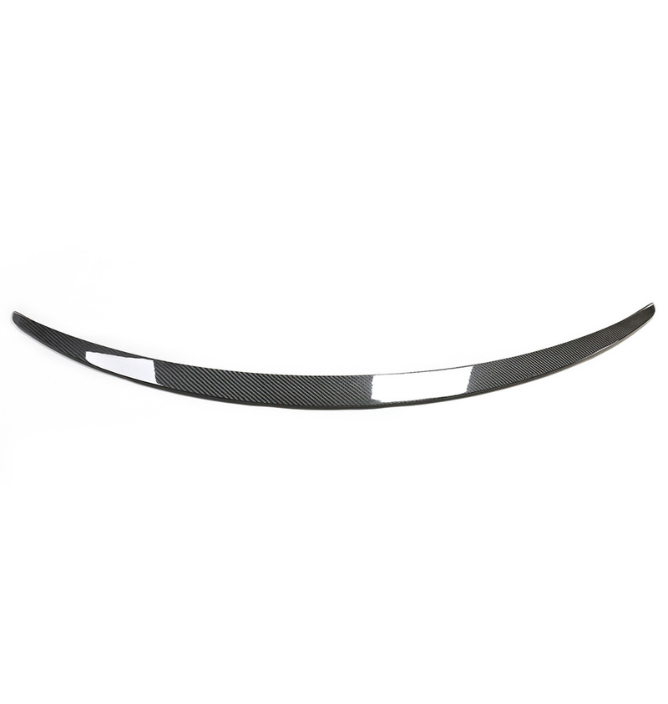 A curved carbon fiber car spoiler lies flat against a plain white background, highlighting its sleek design and lightweight material.