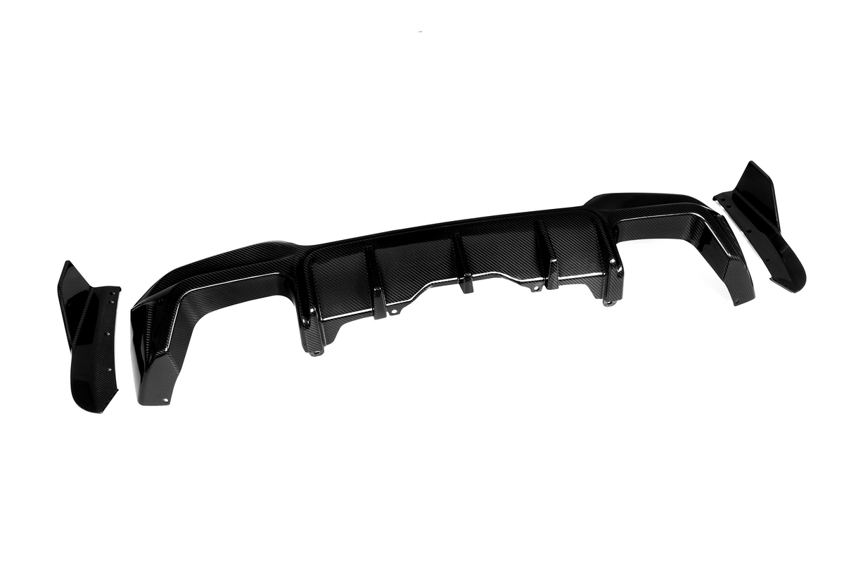 A carbon fiber rear diffuser with fins, designed for aerodynamics, rests on a white background. The set includes side panels detached from the main diffuser piece.