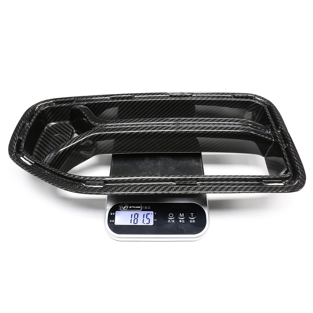 Carbon fiber car part rests on a digital scale displaying "181.5" grams. The scale shows buttons and Asian script, suggesting a precise measurement setting.
