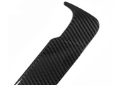 A black carbon fiber car spoiler with a textured pattern rests against a white background, showcasing its aerodynamic design.
