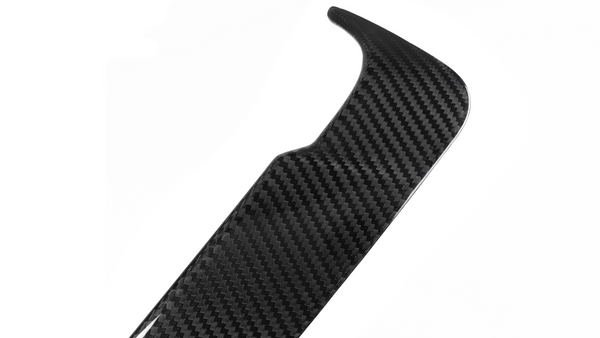 A black carbon fiber car spoiler with a textured pattern rests against a white background, showcasing its aerodynamic design.