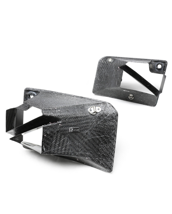Carbon fiber ducts with a textured pattern are positioned against a plain white background. One duct displays a "STILER" label, suggesting a performance automotive application.