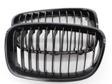 Two black kidney-shaped car grilles with vertical slats are positioned side by side, against a plain white background.