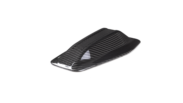 A carbon fiber shark fin antenna rests on a white background, showing a sleek, aerodynamic design with a glossy finish, typically used for vehicles.