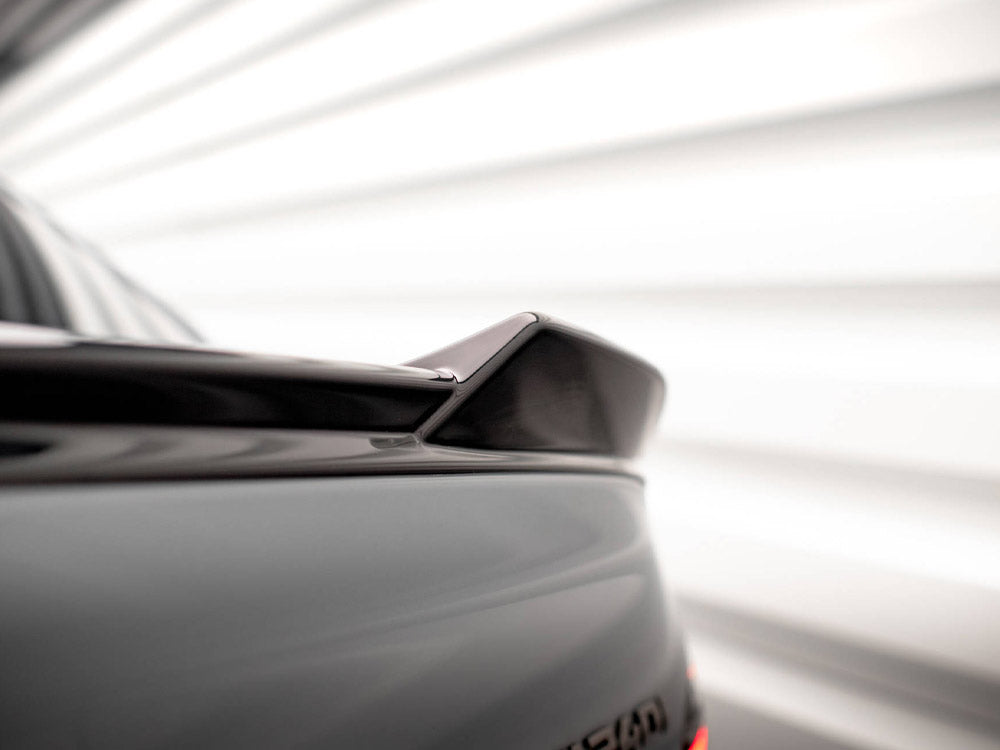 A car rear spoiler is positioned diagonally, set in a blurred, bright background with horizontal lines, suggesting a dynamic, modern environment.