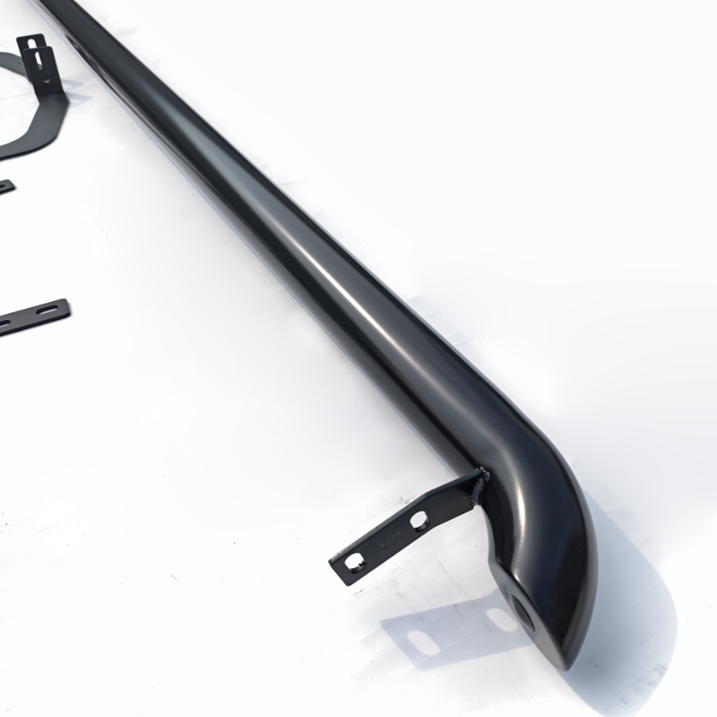 A black, curved metal bar with mounting brackets, positioned diagonally, rests on a smooth, white surface. Additional small metal components are scattered nearby, suggesting assembly or installation.