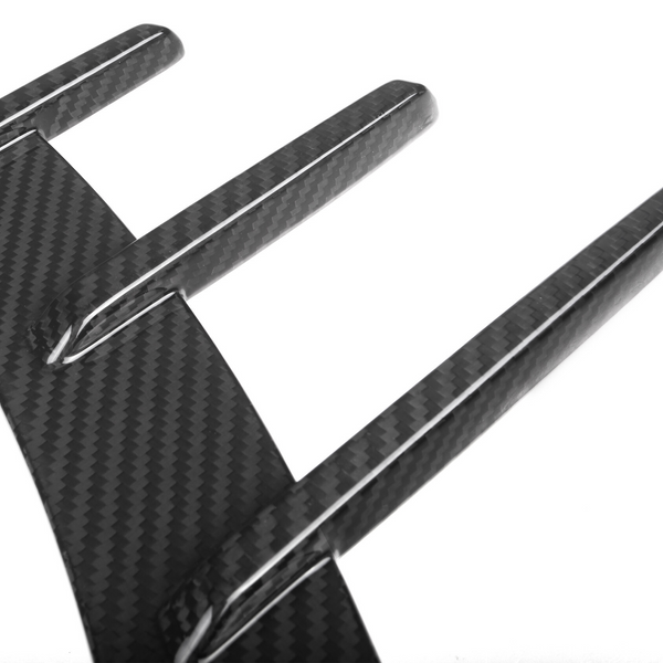 A carbon fiber diffuser with three vertical fins extends outward, angled against a plain white background, showcasing its sleek, aerodynamic design.