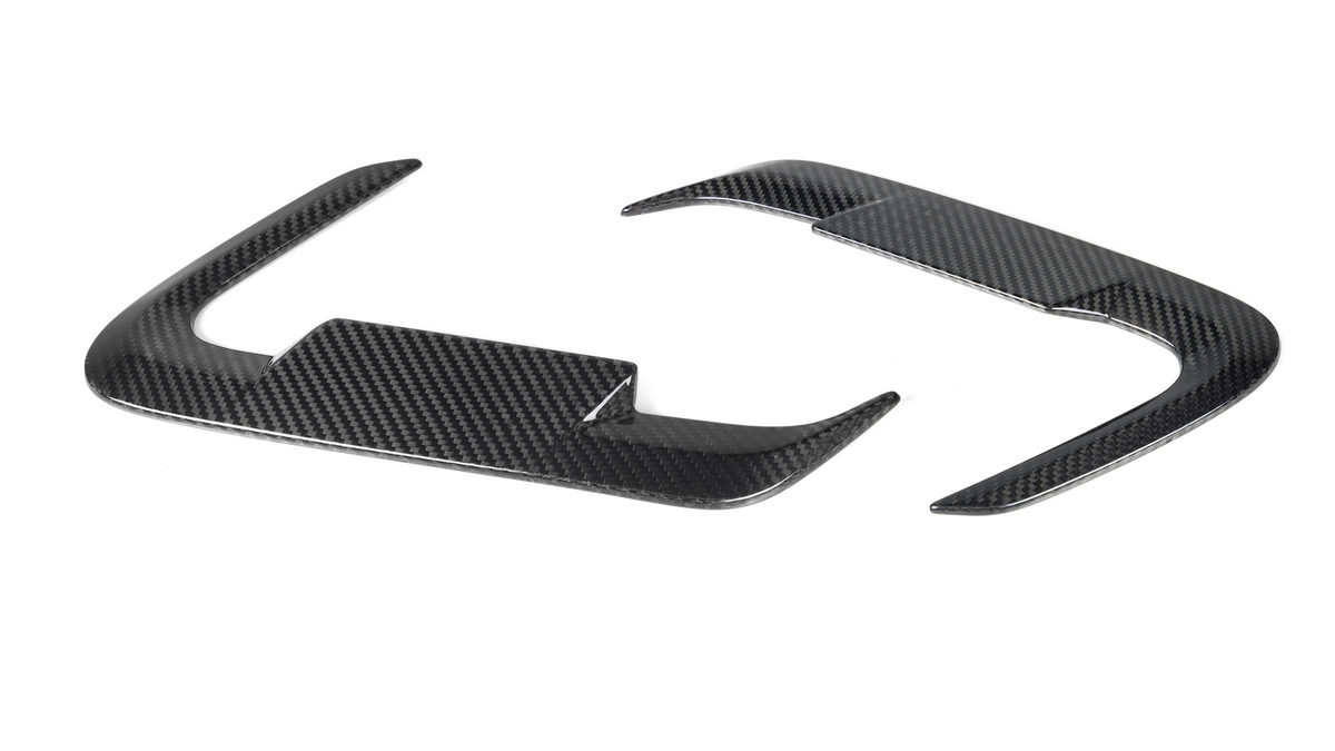 Carbon fiber steering wheel trim pieces, curved and glossy, rest on a plain white background.