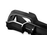 A sleek carbon fiber car part with a glossy finish, featuring angular sections and cutouts, set against a plain white background.
