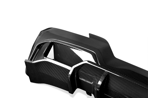 A sleek carbon fiber car part with a glossy finish, featuring angular sections and cutouts, set against a plain white background.