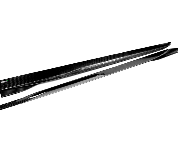 Two sleek, black carbon-fiber side skirts lie parallel on a white background, showcasing their smooth, aerodynamic design ideal for automotive enhancements.