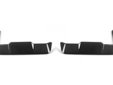 Two black carbon fiber car trim pieces lie side by side, each featuring a sleek, angular design with vertical slits, set against a plain white background.