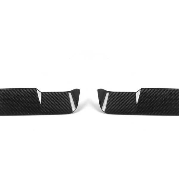 Two black carbon fiber car trim pieces lie side by side, each featuring a sleek, angular design with vertical slits, set against a plain white background.