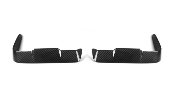 Two black carbon fiber car trim pieces lie side by side, each featuring a sleek, angular design with vertical slits, set against a plain white background.