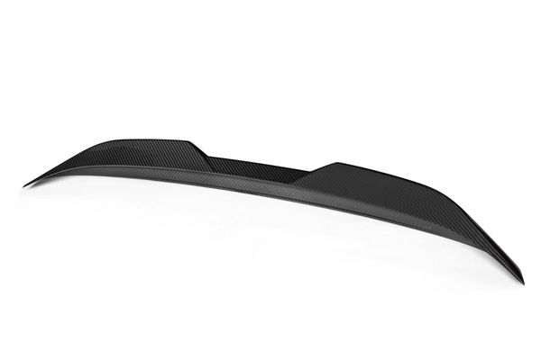 A black carbon fiber car spoiler rests on a plain white background, showcasing a sleek, aerodynamic design with subtle curved contours and a textured finish.