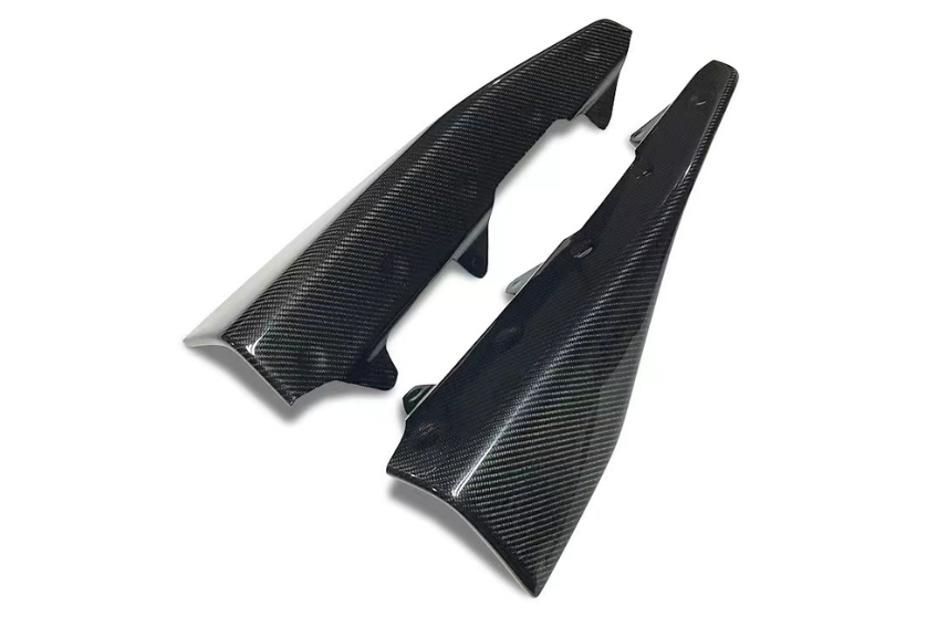 Two carbon fiber motorbike fairing panels lay side by side, angled against a white background, highlighting their glossy, textured finish.