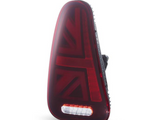 A red car taillight with a Union Jack pattern is positioned upright against a white backdrop, featuring an integrated white rectangular reverse light at the bottom.