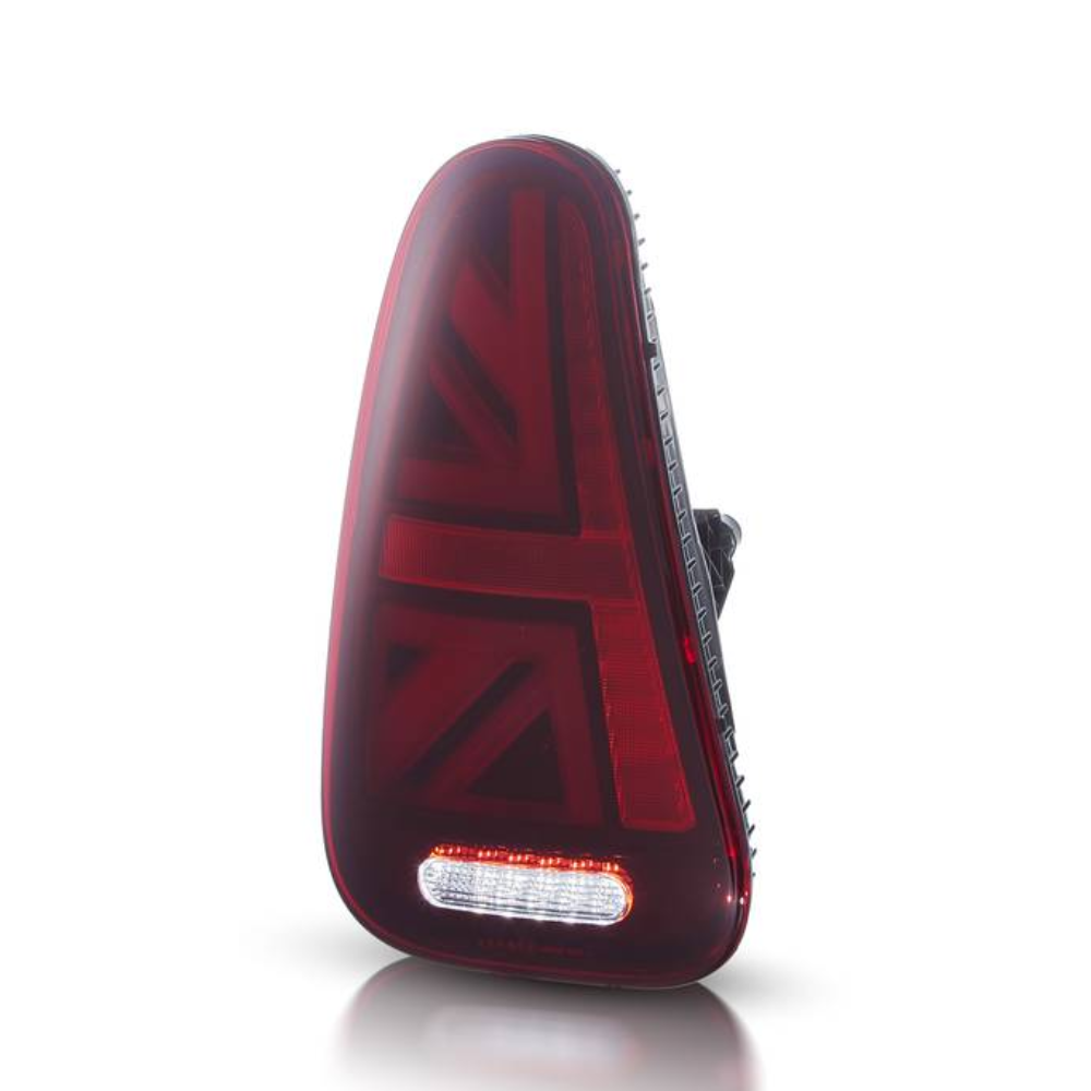 A red car taillight with a Union Jack pattern is positioned upright against a white backdrop, featuring an integrated white rectangular reverse light at the bottom.