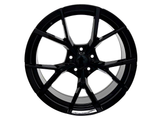 A glossy black alloy wheel with a multi-spoke design is displayed against a plain white background, highlighting its symmetrical, intricate structure and metallic finish.