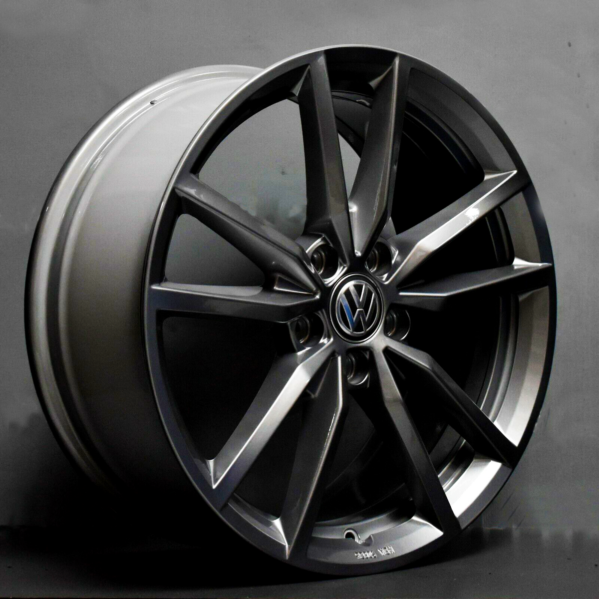 A metallic car wheel rim features a branded emblem in the center, resting against a plain gray background. Text reads "20x8.5J, VW21."