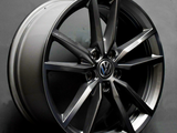 A shiny, multi-spoke car wheel is resting against a dark backdrop, showcasing a Volkswagen logo at its center. The rim is sleek and modern in design.