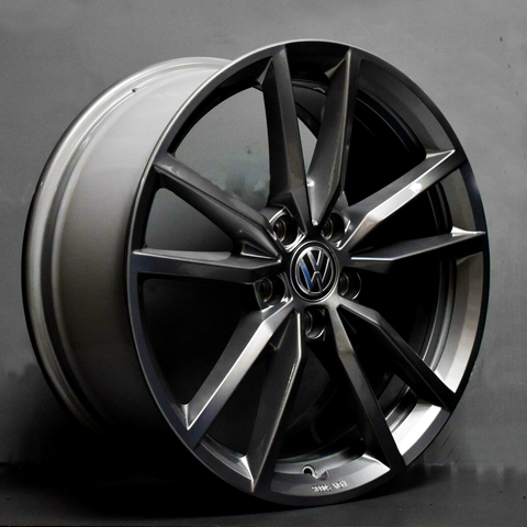 A shiny, multi-spoke car wheel is resting against a dark backdrop, showcasing a Volkswagen logo at its center. The rim is sleek and modern in design.