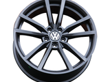 A black alloy wheel, featuring the Volkswagen logo in the center, is displayed against a plain white background.