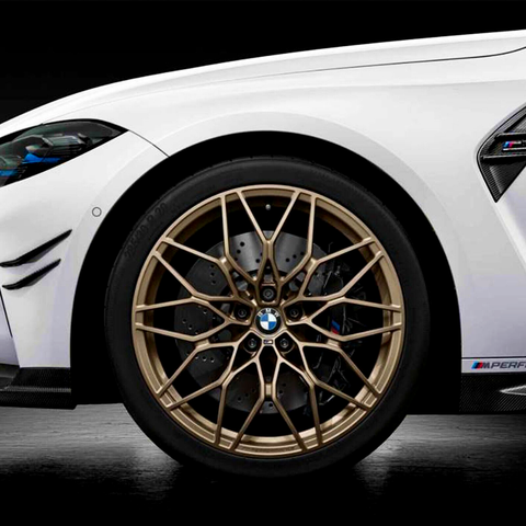 A close-up of a BMW car wheel with intricate gold alloy rim, highlighting the brake disc behind it. The white car body features subtle vents, with a dark, sleek background.