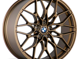 Bronze-colored alloy wheel with intricate split-spoke design, featuring a central logo with 