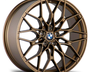 Bronze alloy wheel featuring a starburst pattern and BMW emblem at center, displayed on a white background.