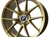 A gold alloy wheel with a central BMW logo and 
