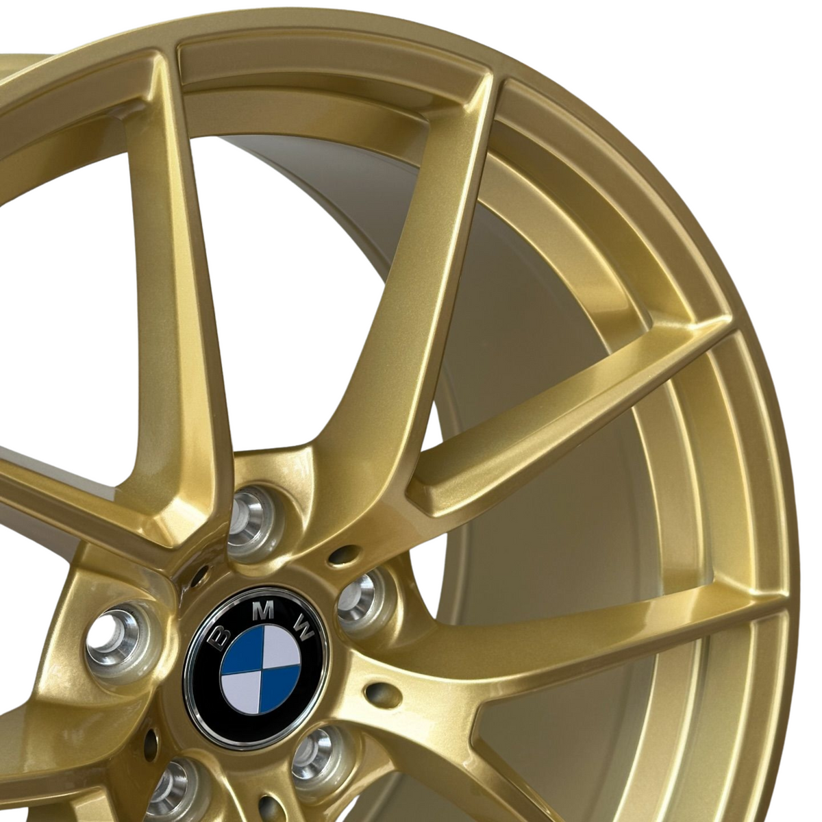 A gold alloy wheel with a five-spoke design prominently features the BMW logo in the center, surrounded by metallic detailing. It is presented against a plain background.