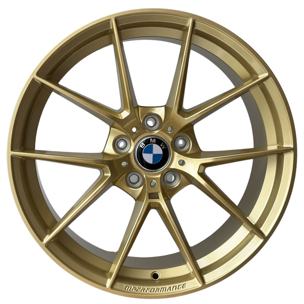 A gold alloy wheel with a black and white BMW logo at the center. The rim is marked "M PERFORMANCE." It features a multi-spoke design against a white background.