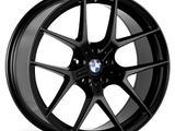 A black BMW alloy wheel with a multi-spoke design is positioned against a plain white background, highlighting its sleek and polished appearance. The BMW logo is visible at the center.