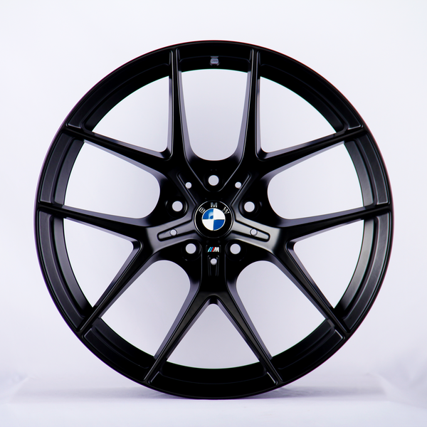 A black car wheel rim with a BMW logo in the center is displayed against a plain white background, emphasizing its sleek, modern design.