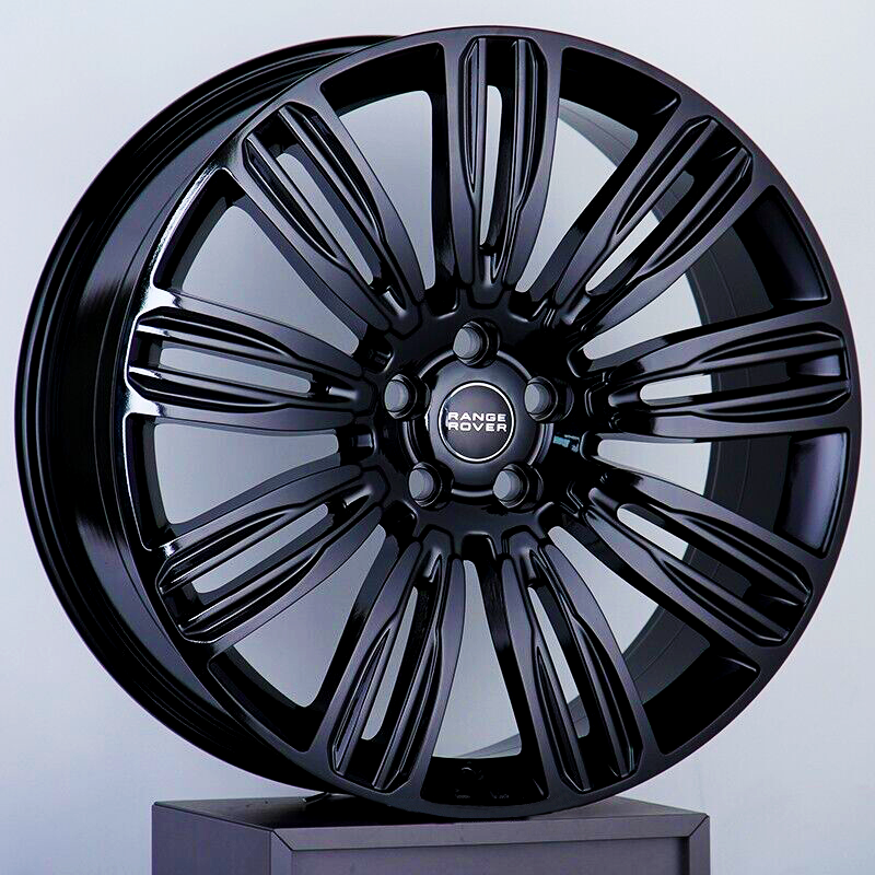 A black alloy wheel with a multi-spoke design rests on a gray pedestal. The center is embossed with "Range Rover" text, highlighting its brand association.