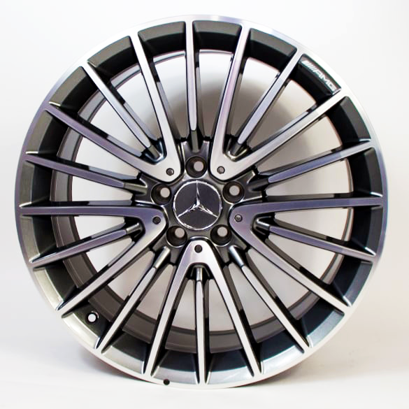 A silver and black alloy wheel with a Mercedes-Benz emblem and an AMG badge, featuring multiple spokes, positioned against a plain white background.