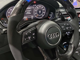 A carbon fiber steering wheel with illuminated indicators displays readings of 