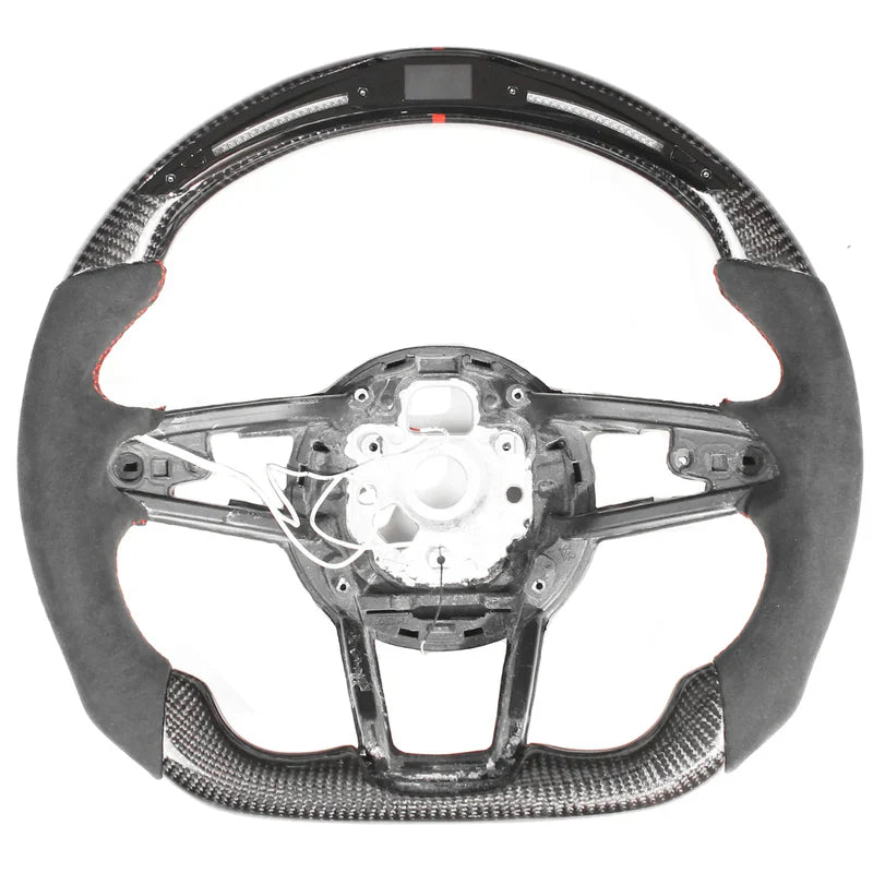 The object is a racing-style car steering wheel with carbon fiber and suede trim. The central section is unfinished, showing wiring and mounting points, against a plain white background.