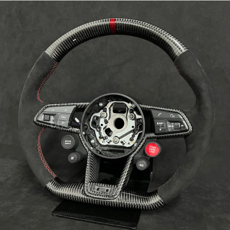 A carbon fiber steering wheel with black and red accents is displayed against a dark background. It features several buttons including "drive mode" and "START ENGINE STOP."
