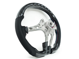 A carbon fiber car steering wheel frame with black perforated grips sits on a plain white background, showcasing exposed metal structure and colorful stitching on the grips.